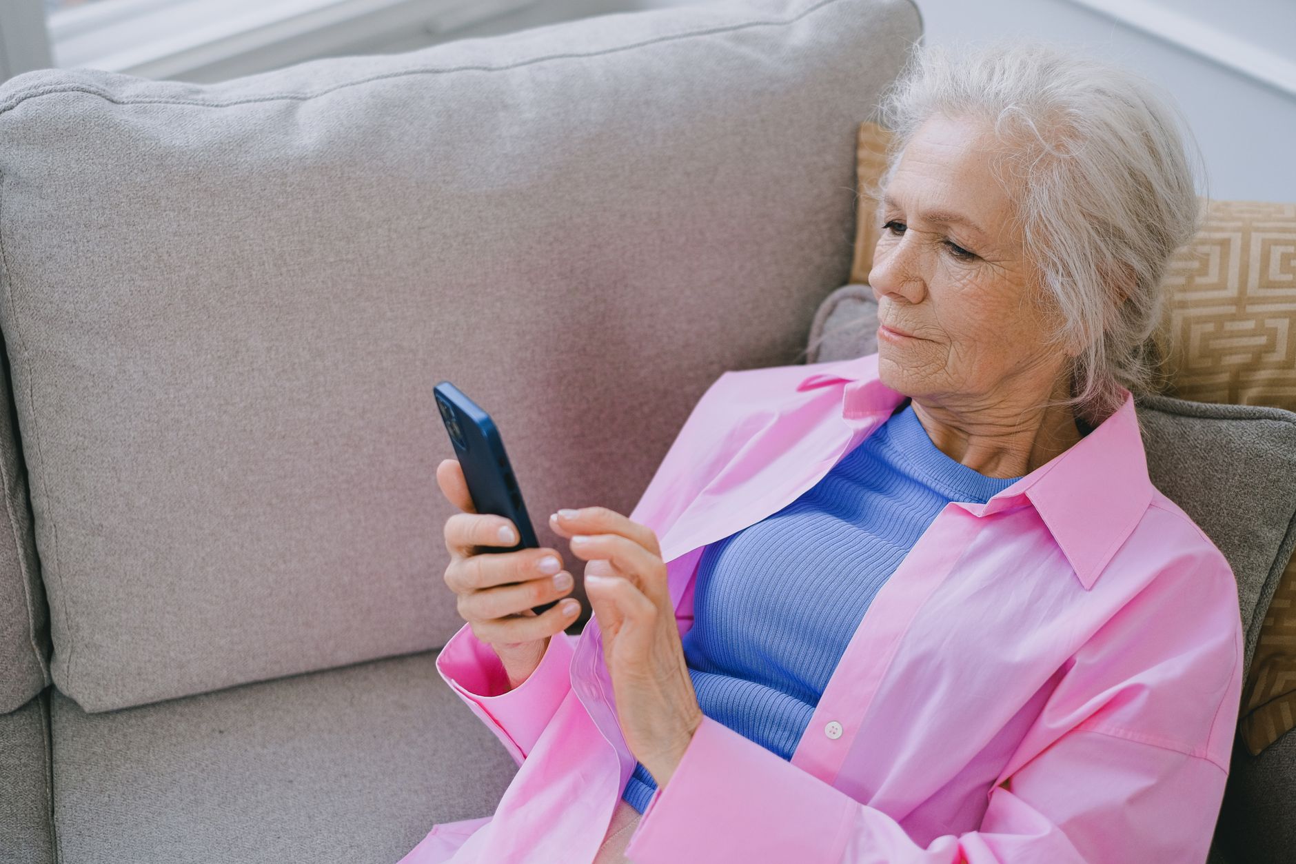 An older adult installing a call blocker app from the App Store on a smartphone.
