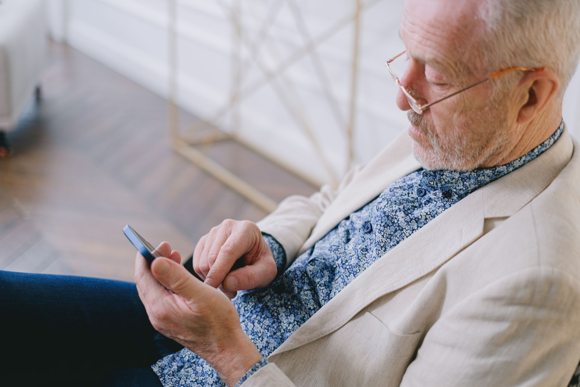 A senior man reading a news article on a smartphone with large text in the browser.