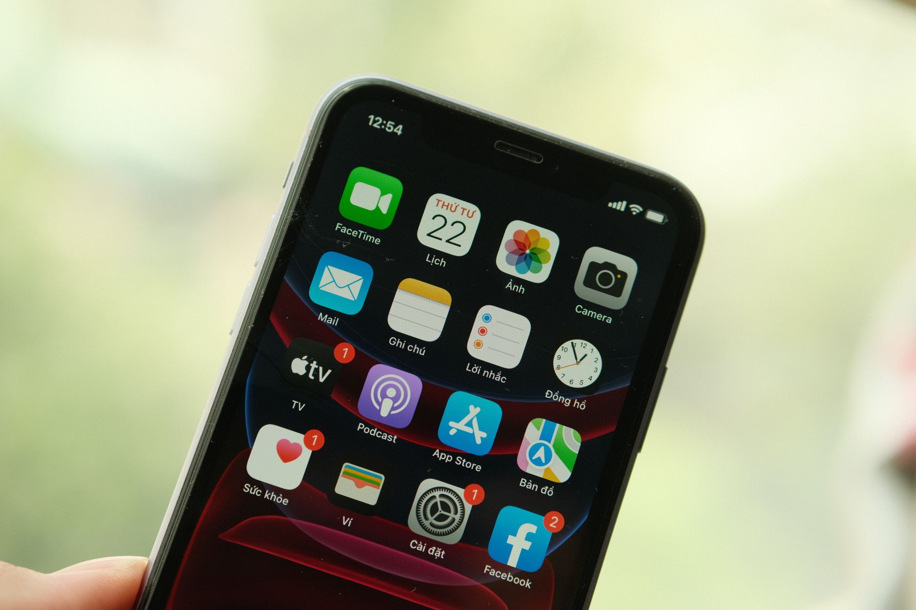 a person holding a smartphone with the FaceTime app icon visible