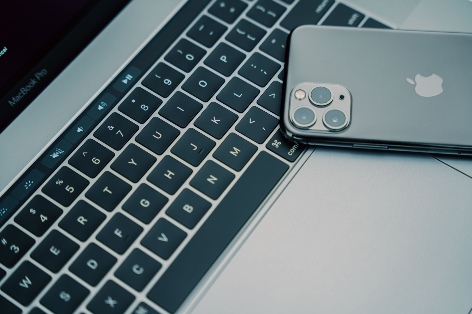 a person holding an iPhone near a MacBook with AirDrop accept prompt on screen