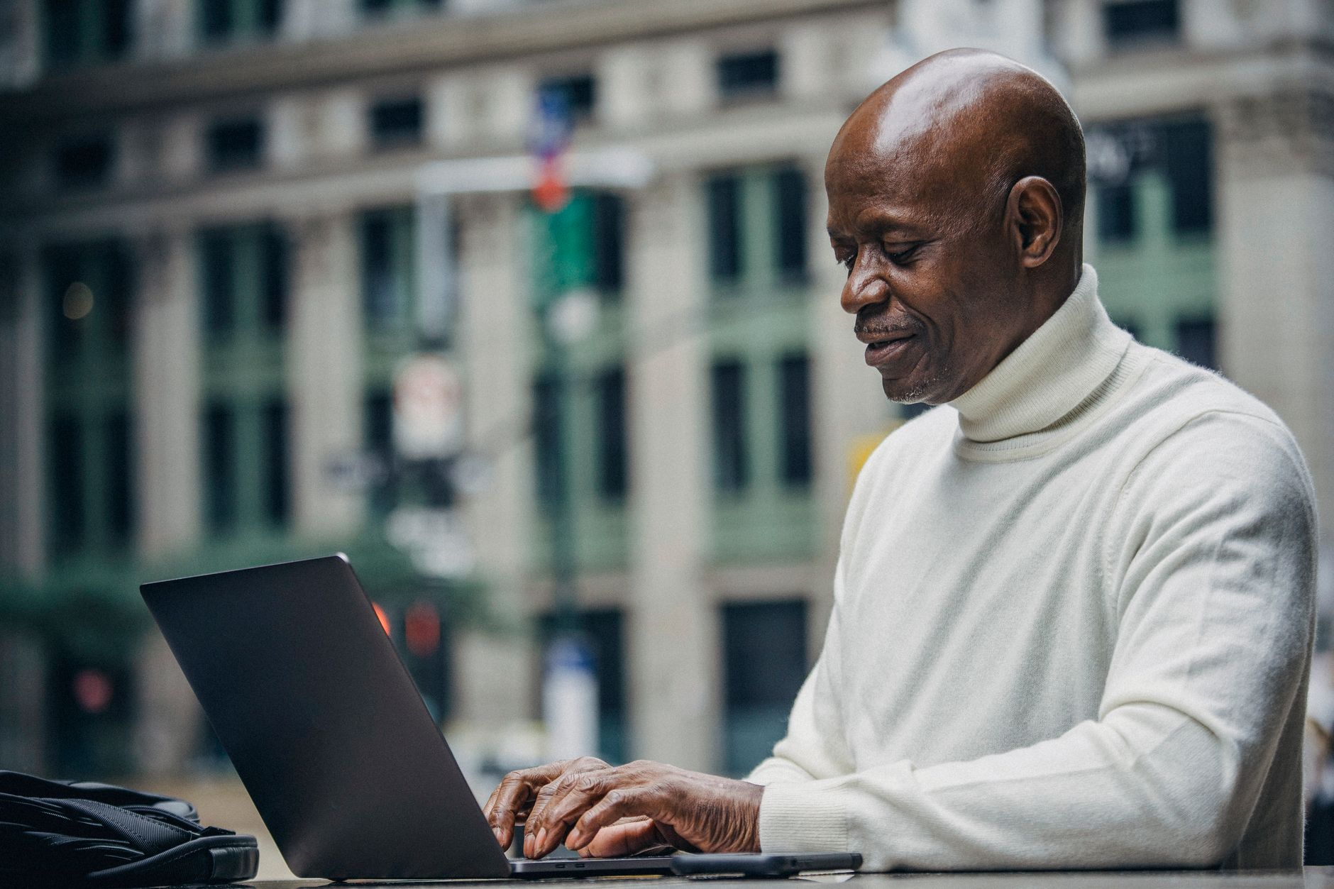 a senior man typing a strong password on a laptop with a bank login page on the screen